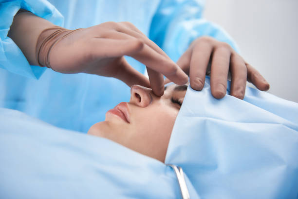 A surgeon examining a patient's nose during rhinoplasty surgery in an operating theatre in Bangkok, Thailand.
